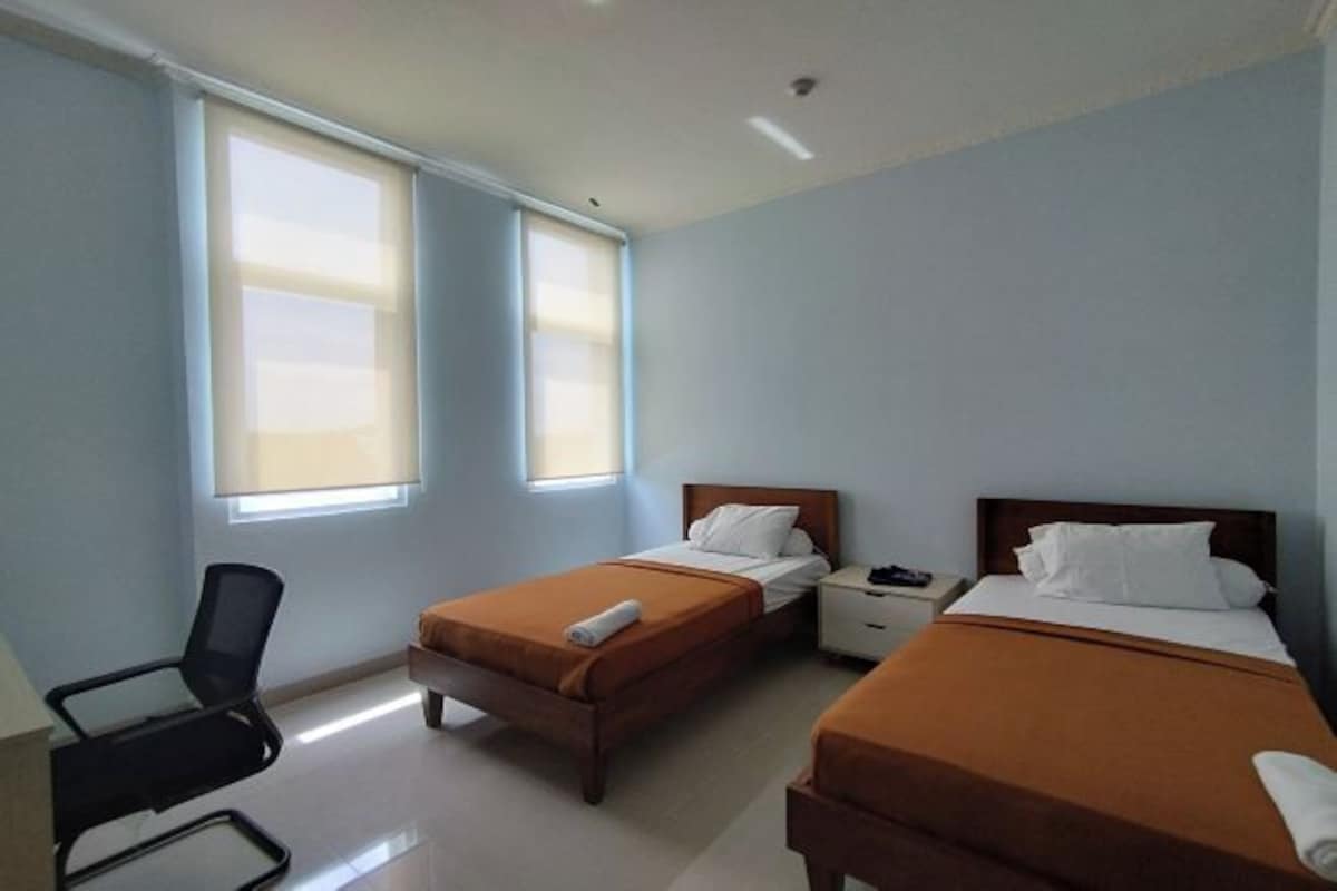 Habitación de hotel con dos camas, un escritorio y una silla.