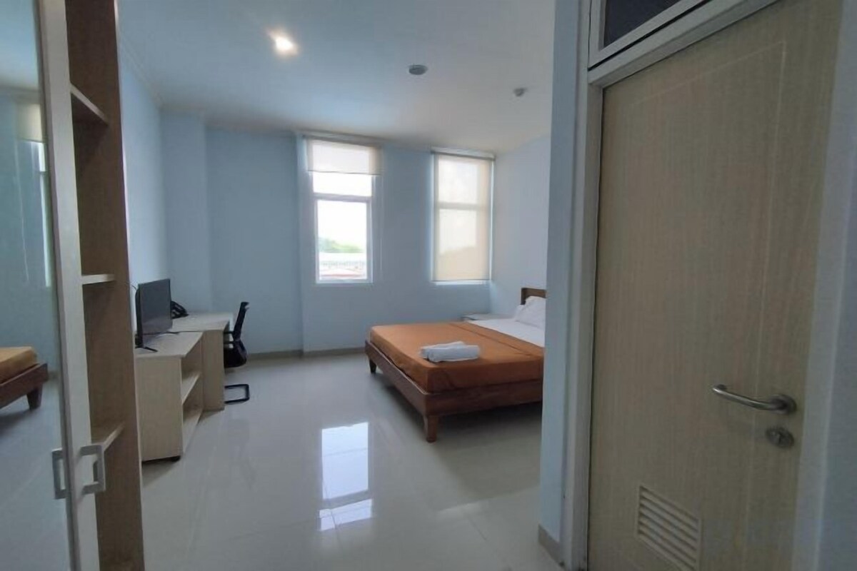 A bedroom with a bed, a desk, a chair, and a computer.