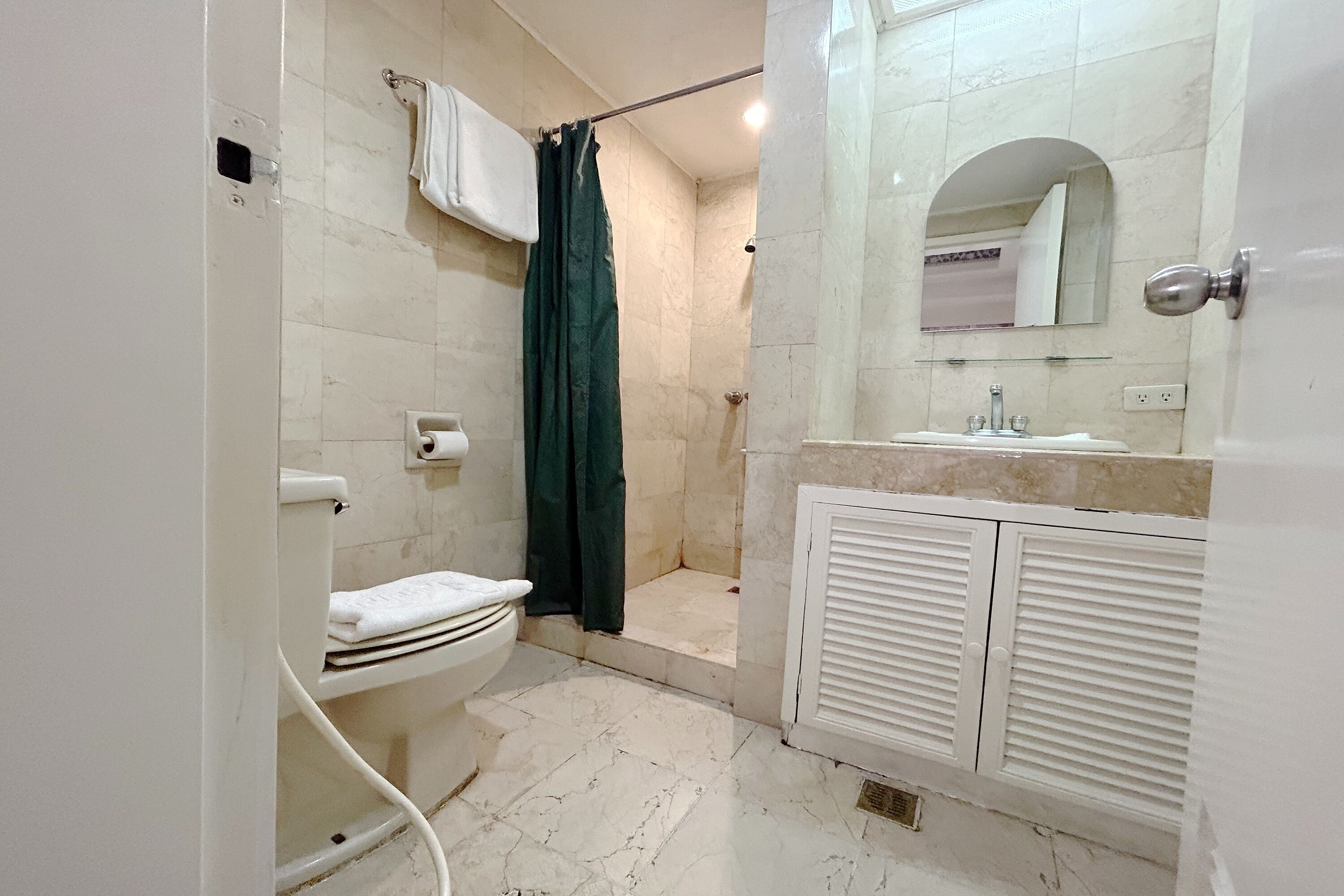A bathroom with a toilet, shower, and sink.