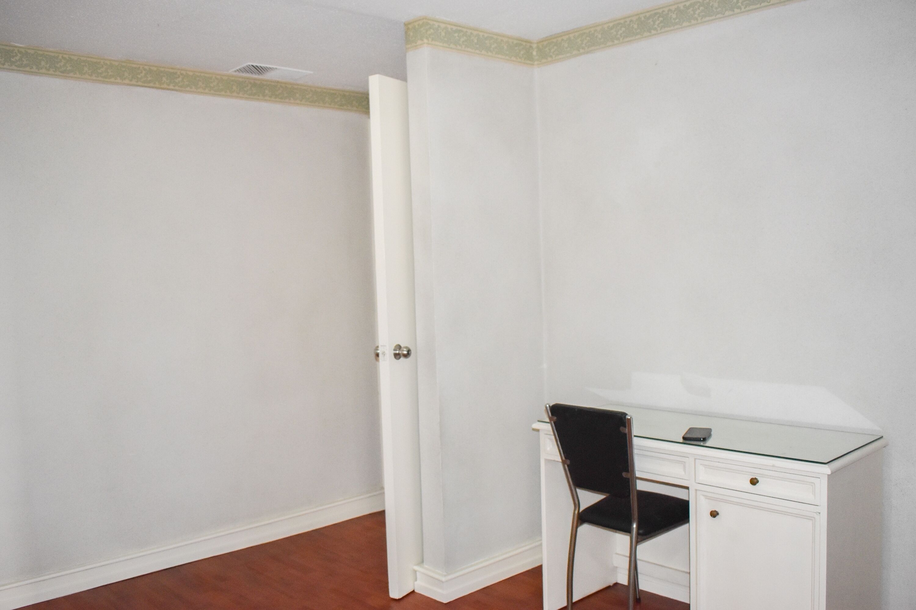 A room with a closed door, a desk with a chair, and a small table.