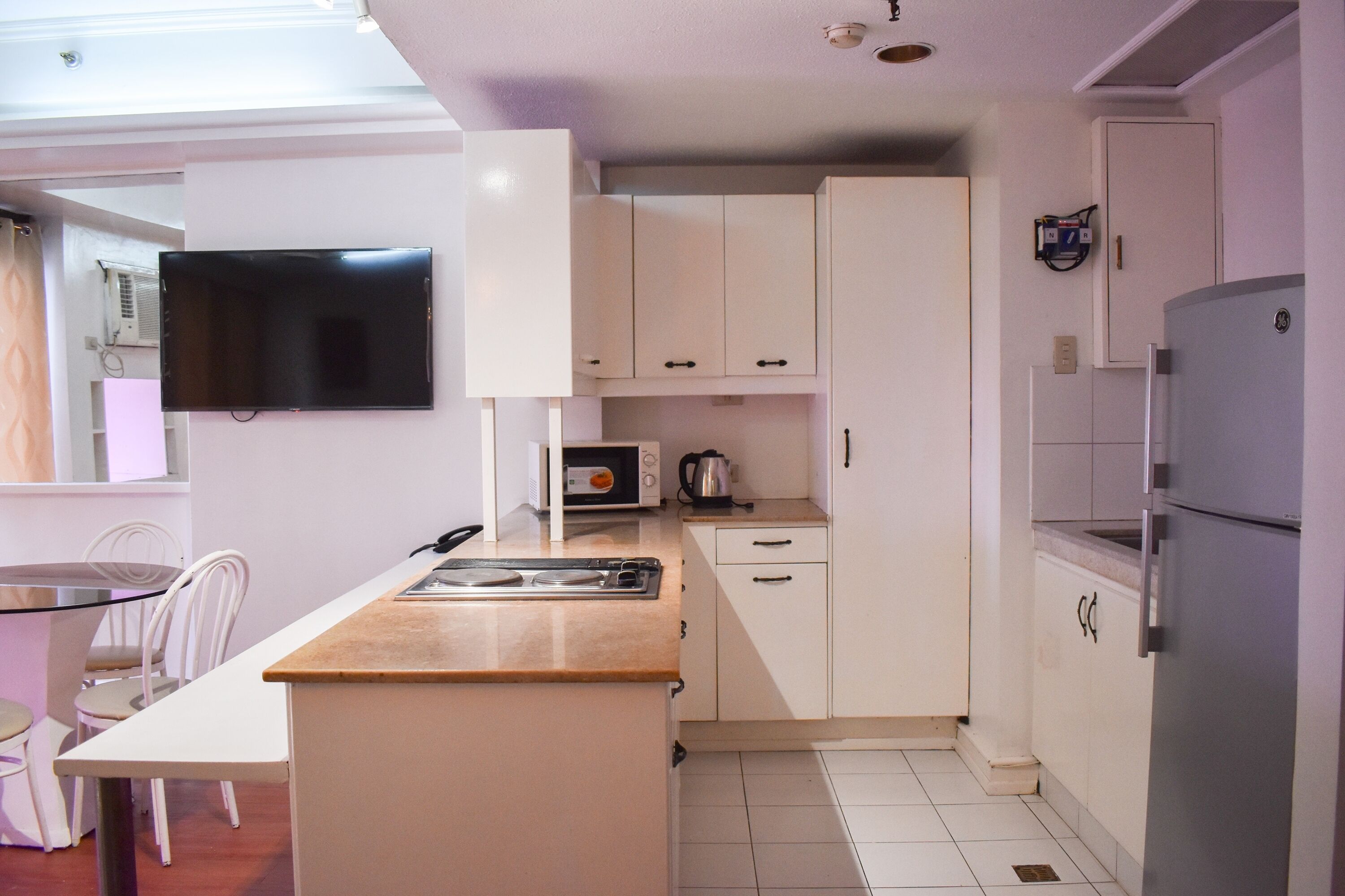 A compact kitchen with white cabinets, a built-in microwave, a stove, and a refrigerator.