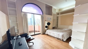 Une chambre d’hôtel équipée d’un bureau, d’un lit, d’une grande fenêtre avec des rideaux et offrant une vue sur la ville.