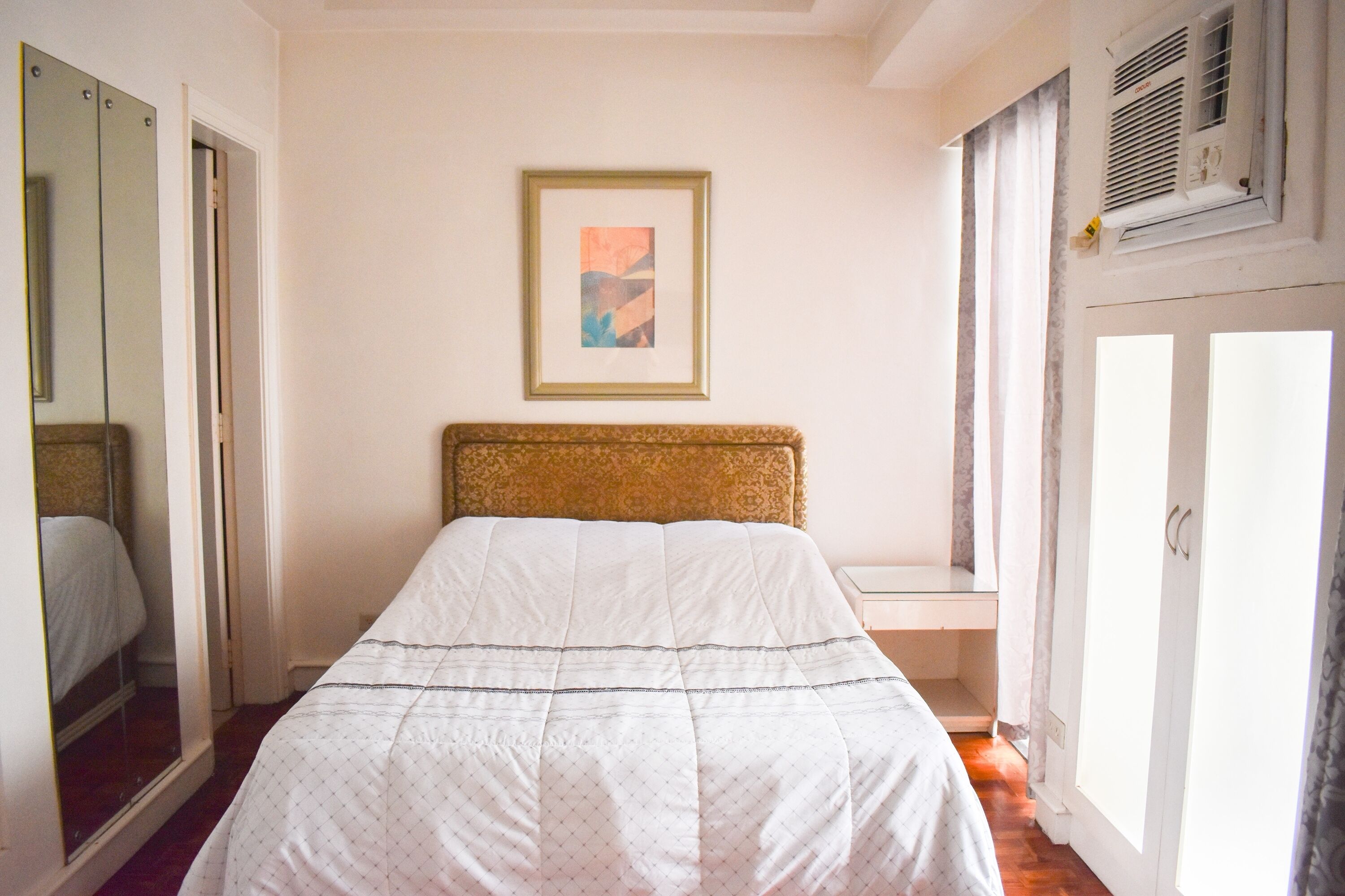 Une chambre à coucher avec un lit, un tableau encadré au mur et une armoire.