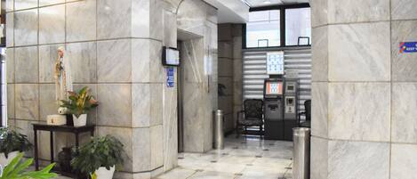A lobby with marble flooring, a reception desk, potted plants, and a sign indicating a keep-your-key area.