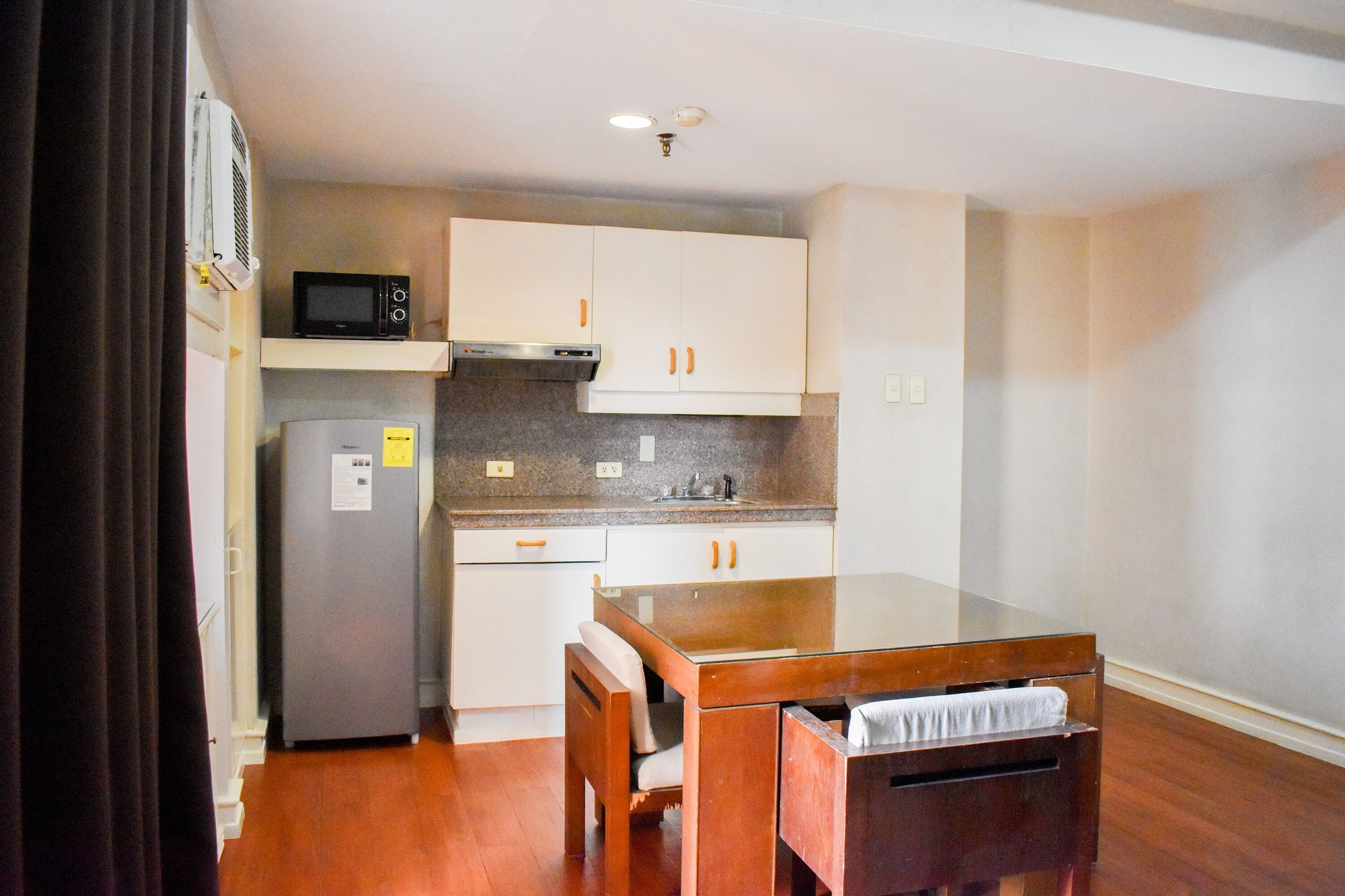 A compact kitchen with a microwave, refrigerator, and wooden table with chairs.