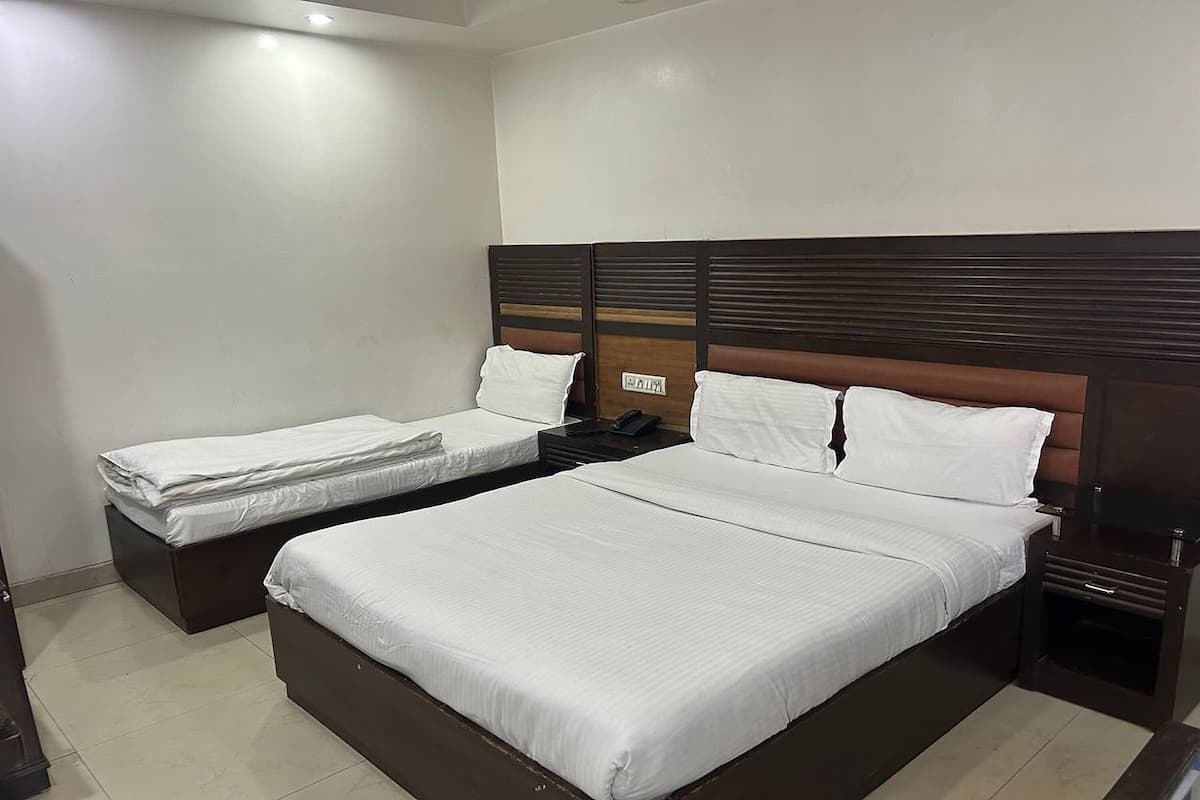 A hotel room with two single beds and a larger double bed.