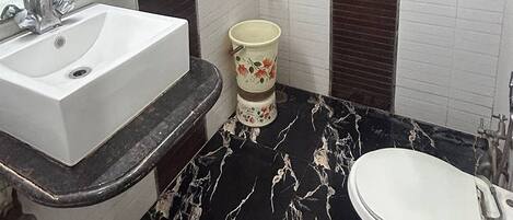 A bathroom with a white sink, a toilet, and a shower area.