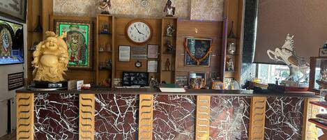 A reception desk with a clock, framed artwork, and various decorative items.