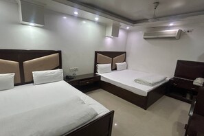 A hotel room with two beds, a nightstand, a dresser, and an air conditioning unit. - Hotel Today International (New Delhi)