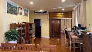 A dining area with wooden furniture, a potted plant, and a cabinet with dishes. - Baan Wang Tarn (Hang Dong)