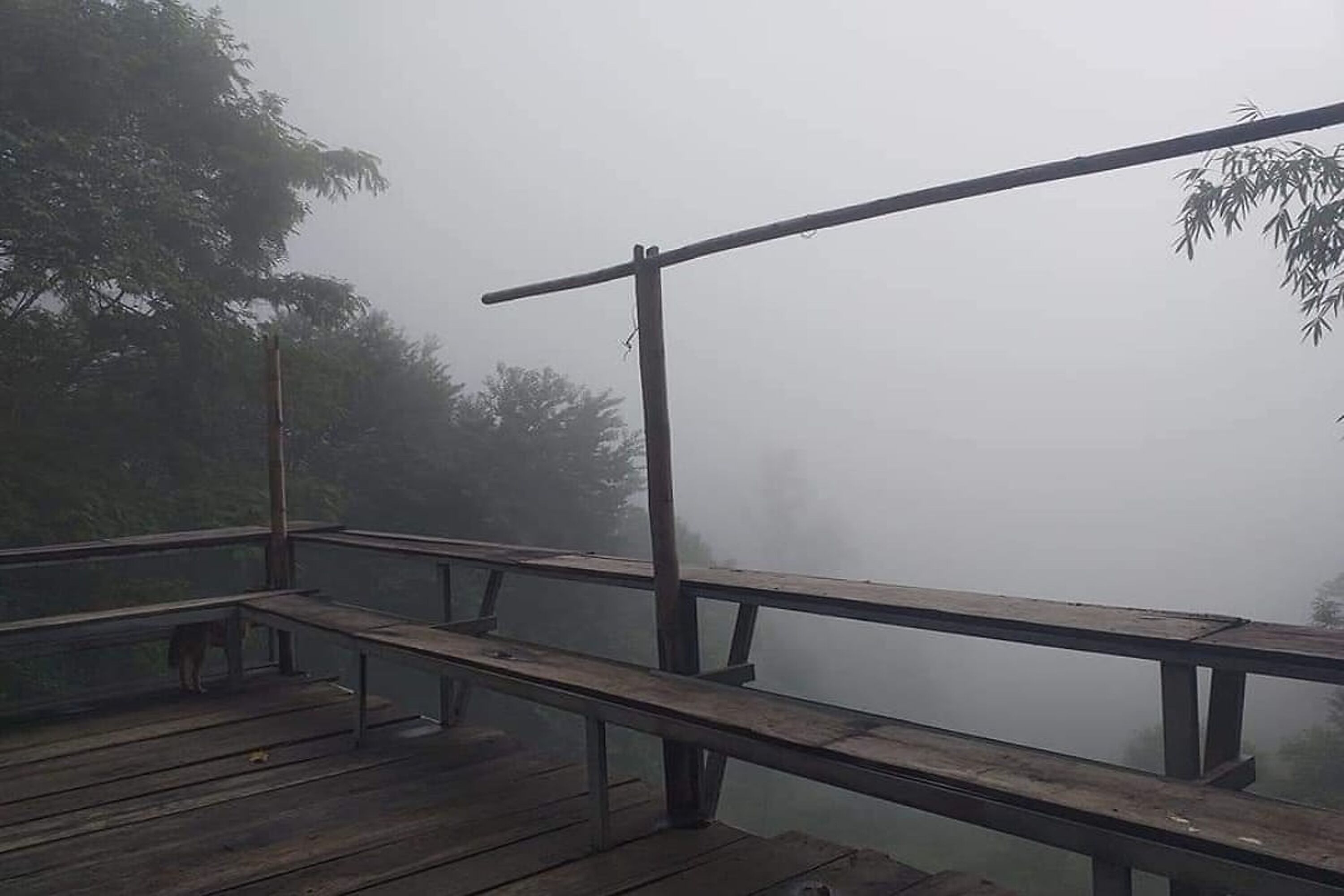 A wooden deck with railings overlooking a misty landscape.