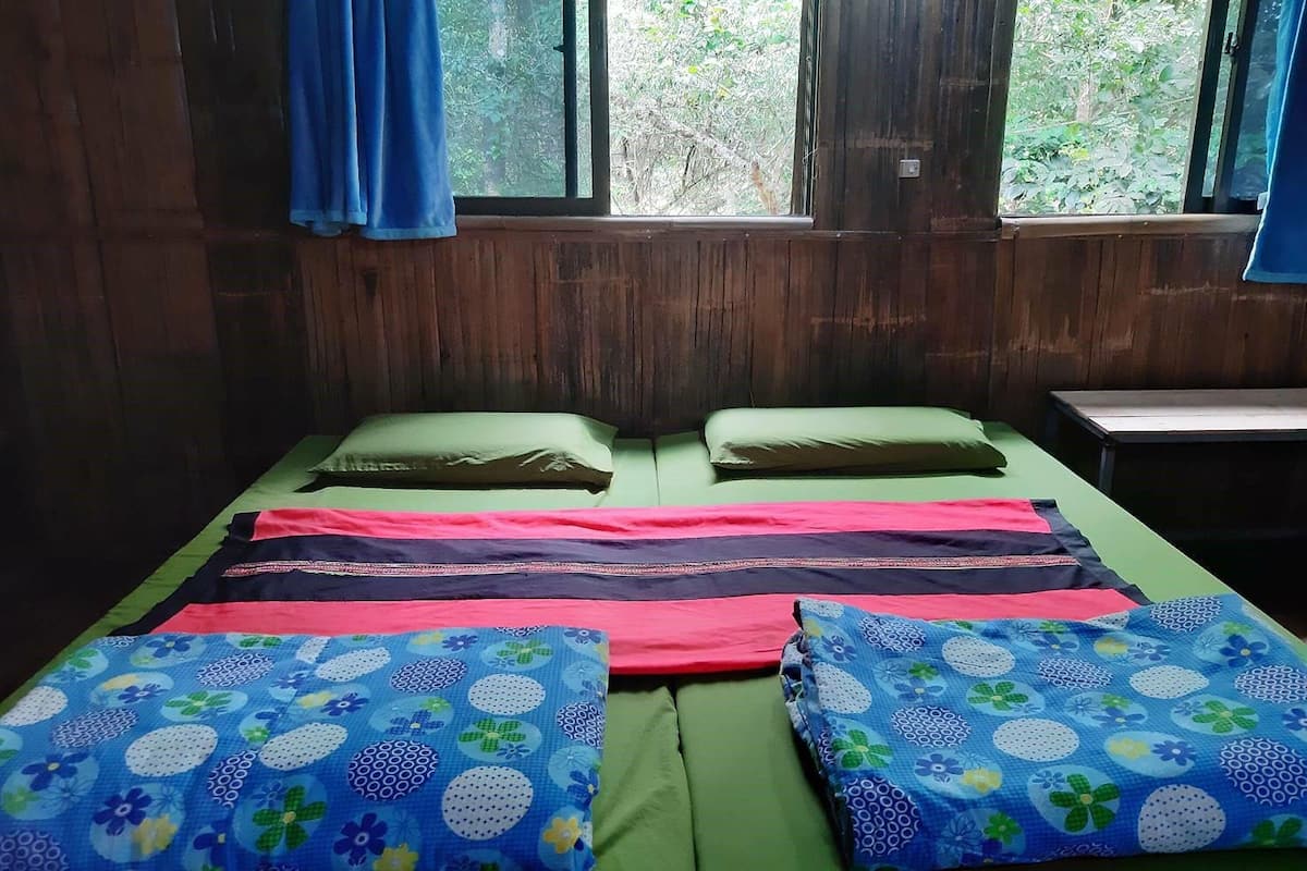 Una habitación con una cama, ropa de cama verde y una ventana con cortinas.
