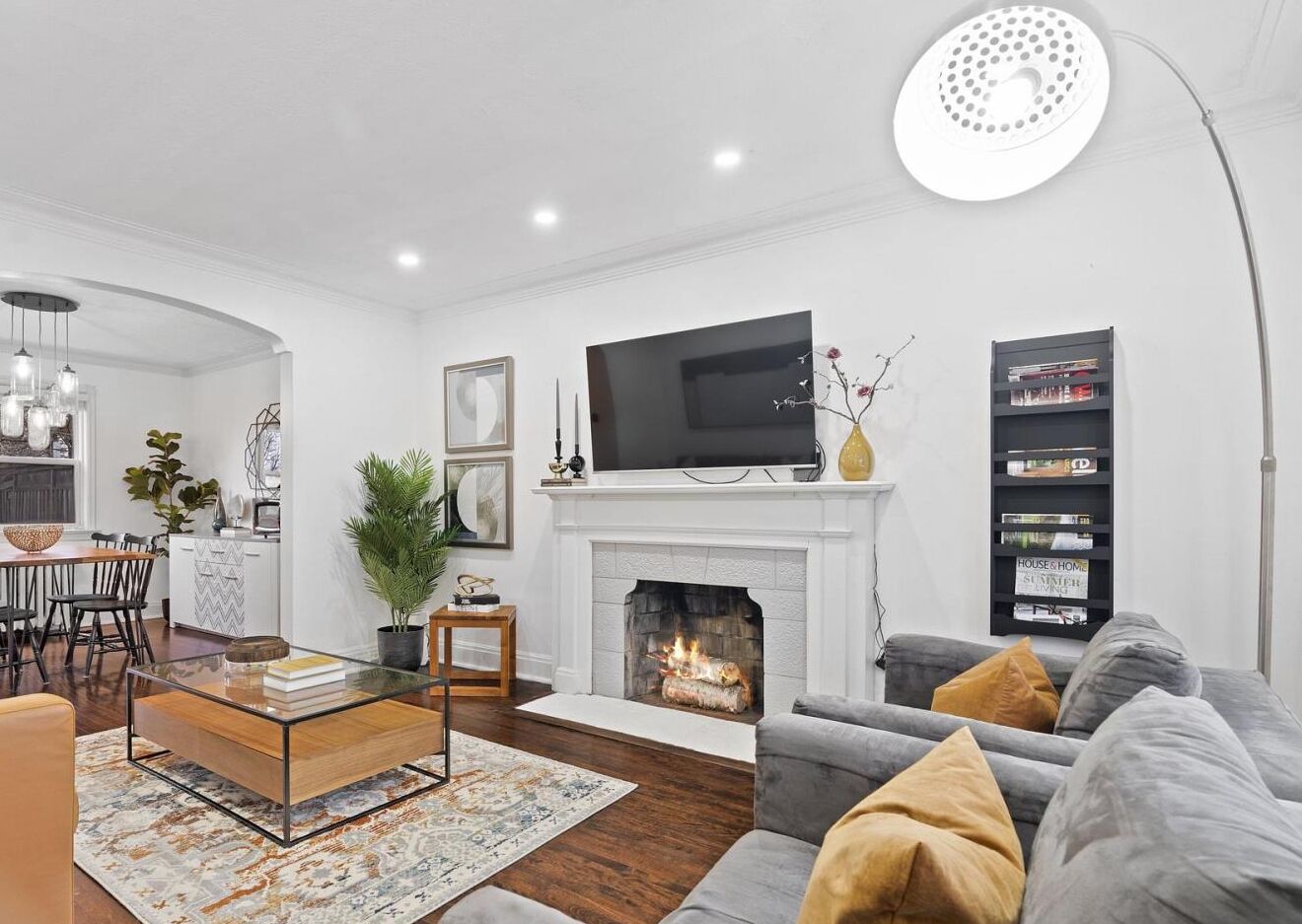 Una sala de estar moderna con chimenea, televisor de pantalla plana, comedor y estantería.