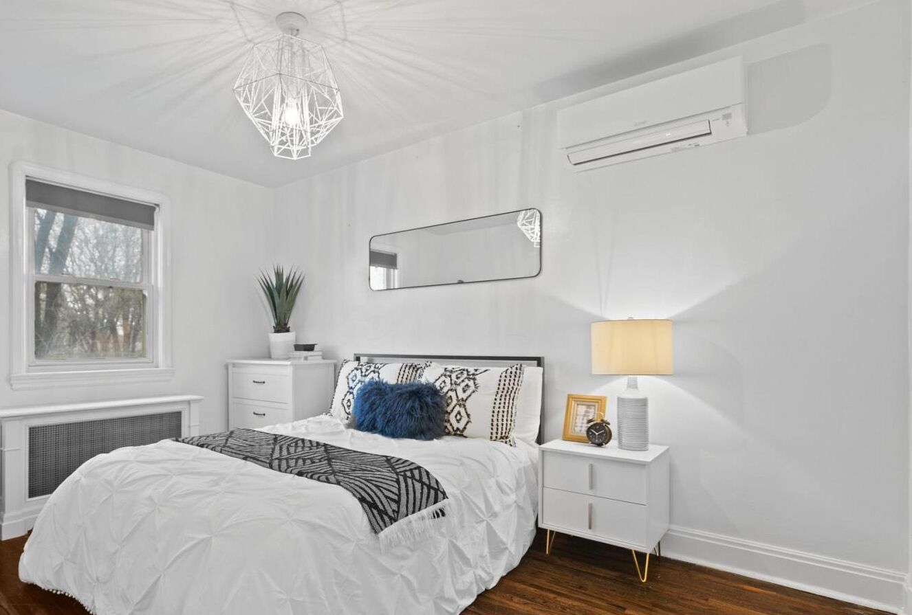Une chambre à coucher avec un lit, une table de chevet, une lampe et une fenêtre.