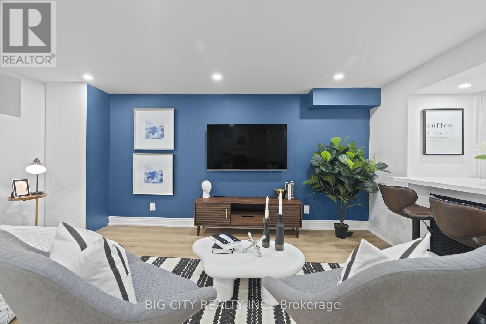 A modern living room with a blue accent wall, a large flat-screen TV, a coffee table, and a sofa.