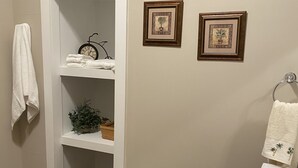 A bathroom with a white vanity, a towel rack, and two framed pictures on the wall. - Historic McDonald Airbnb (Attica)