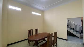 A dining area with a wooden table and chairs, a ceiling with decorative elements, and a staircase in the background.
