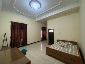 A bedroom with a bed, a desk, and a chair. - Omah Sawah Homestay (Sleman)
