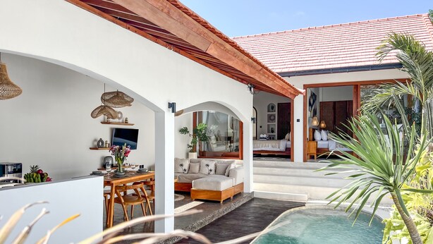 Una casa moderna con piscina, comedor y sala de estar con sofá y mesa de centro.