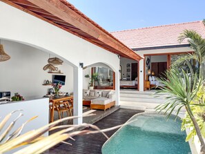 Une maison moderne dotée d’une piscine, d’un coin repas et d’un salon avec un canapé et une table basse.