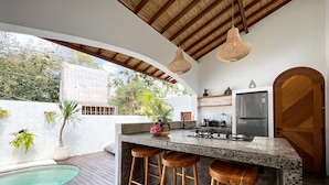 Una cocina moderna con una isla grande, taburetes de bar y una zona de piscina.