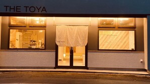 Exterior del The Toya, un café y bar de diseño moderno con amplios ventanales.