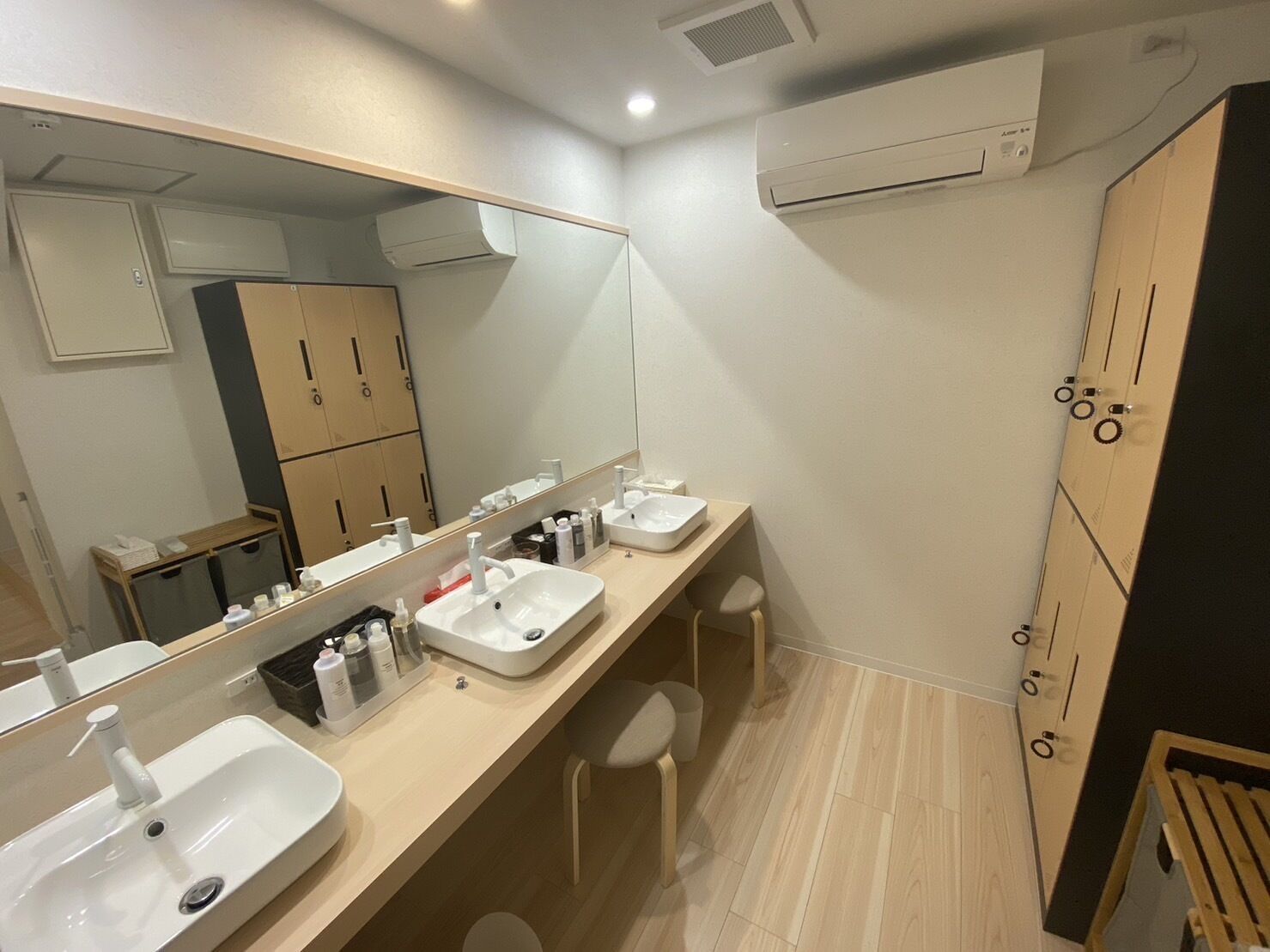 A modern bathroom with two sinks, a large mirror, and a wooden cabinet.