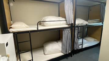 Een slaapkamer met een stapelbed met drie niveaus, elk voorzien van een matras en kussens.