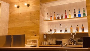 Zona de bar con techo de madera y estantes llenos de botellas de licores.