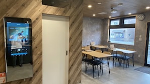 Un interior moderno con paredes de madera, un reproductor de música digital y un comedor con mesas y sillas.