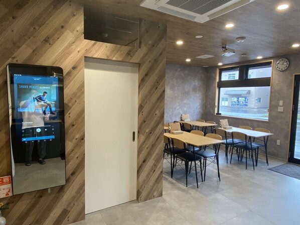 A modern interior with wooden walls, a digital music player, and a dining area with tables and chairs.