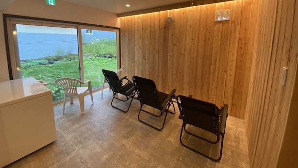 Una habitación con una pared de madera, un ventanal grande y tres sillas.