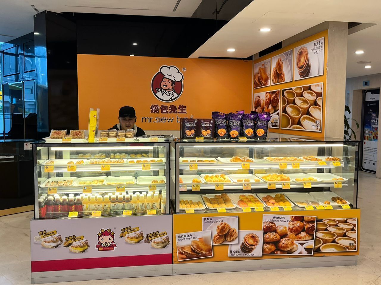 Une vitrine de boulangerie présentant diverses pâtisseries et le logo de l’établissement, qui est un chapeau de chef.