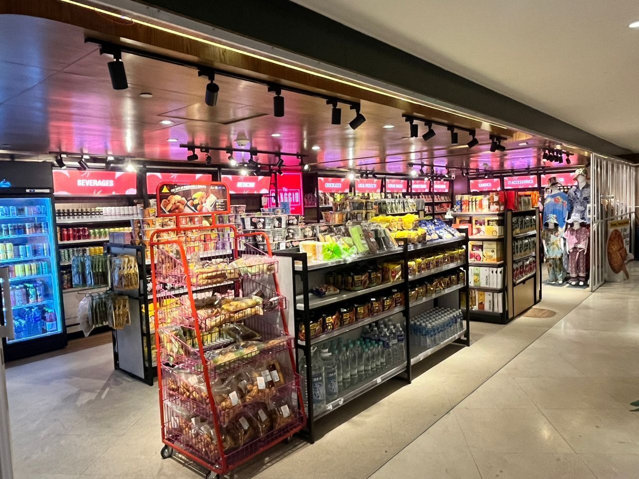 A well-lit convenience store with refrigerated sections, shelves stocked with snacks, and a variety of packaged goods.