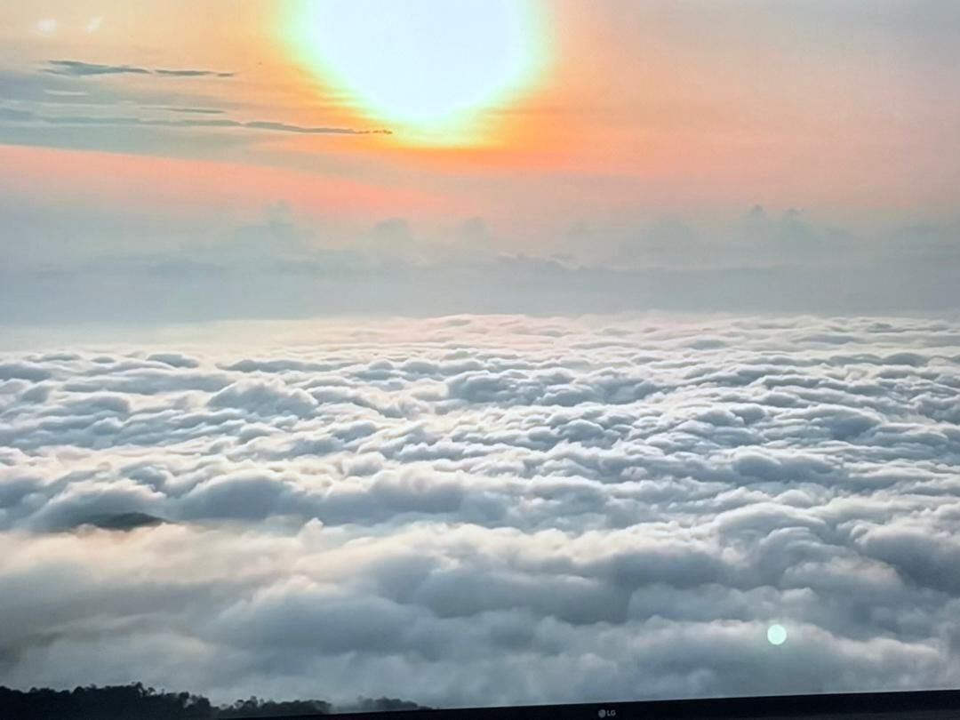 Aussicht auf Wolken von oben, mit sichtbarer Sonne am Himmel.