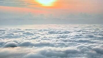 Aussicht auf Wolken von oben, mit sichtbarer Sonne am Himmel.