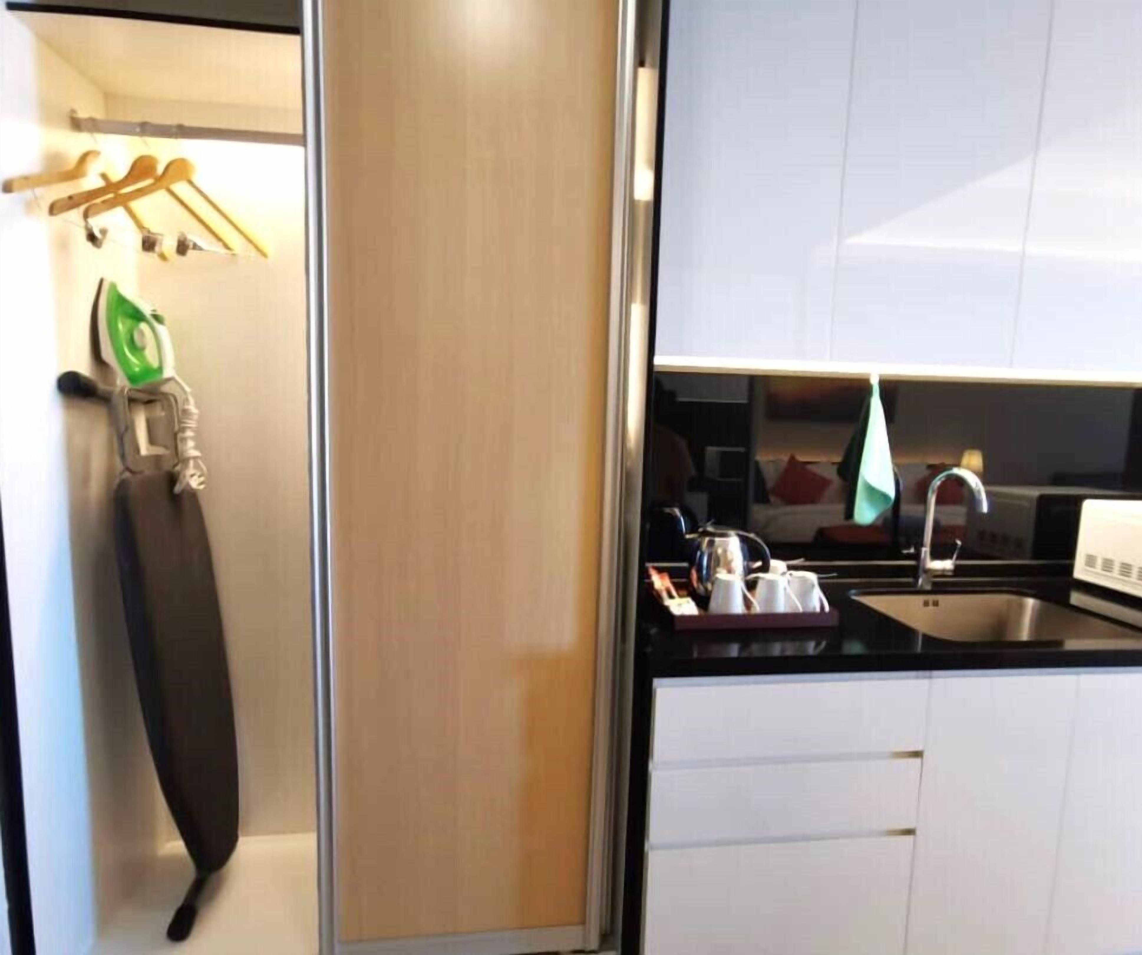 Una cucina moderna con mobili bianchi, un lavello in acciaio inossidabile e un bollitore sul piano di lavoro.