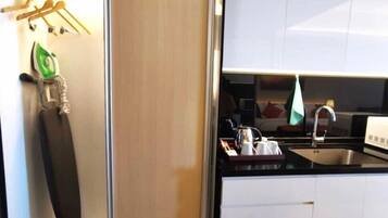 Una cucina moderna con mobili bianchi, un lavello in acciaio inossidabile e un bollitore sul piano di lavoro.