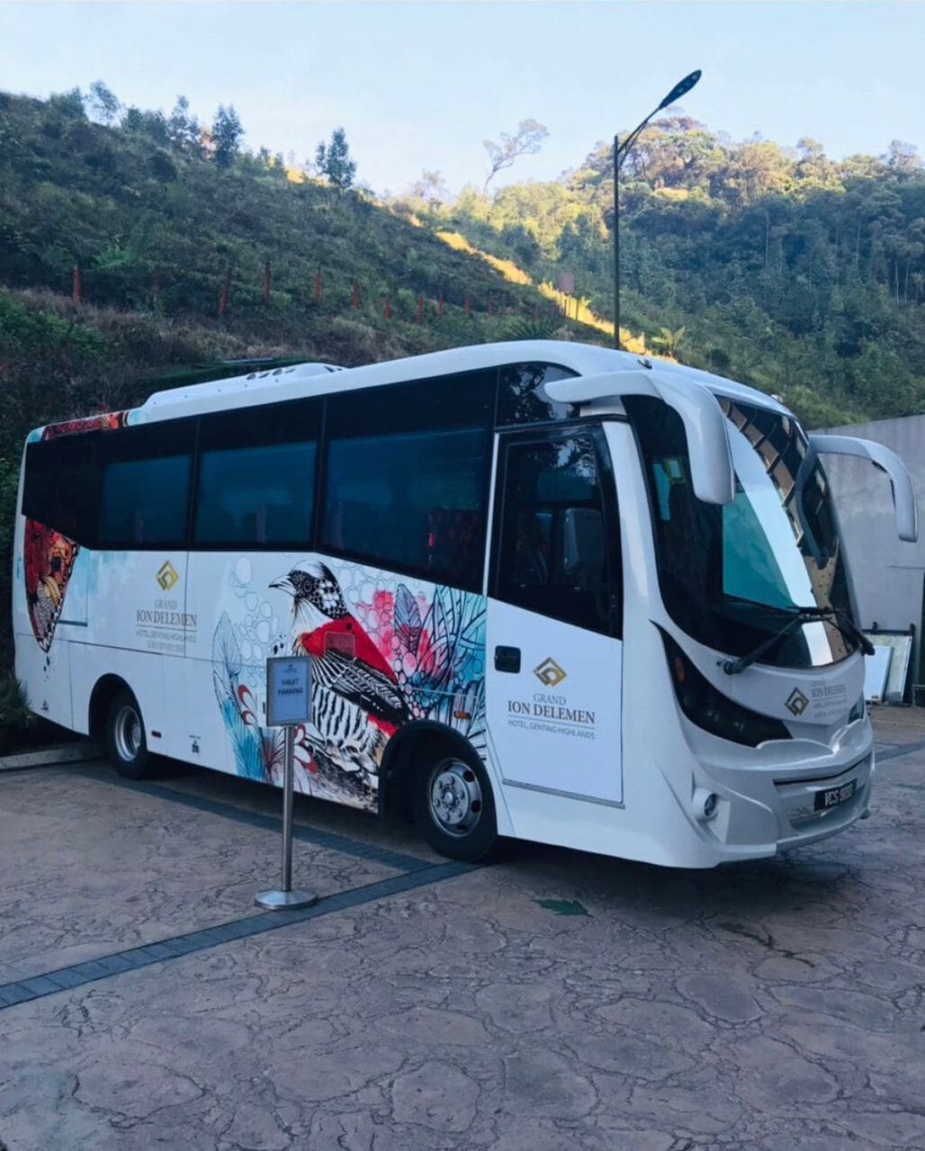 A white bus with "Grand Ion Delemen" branding parked on a paved area.
