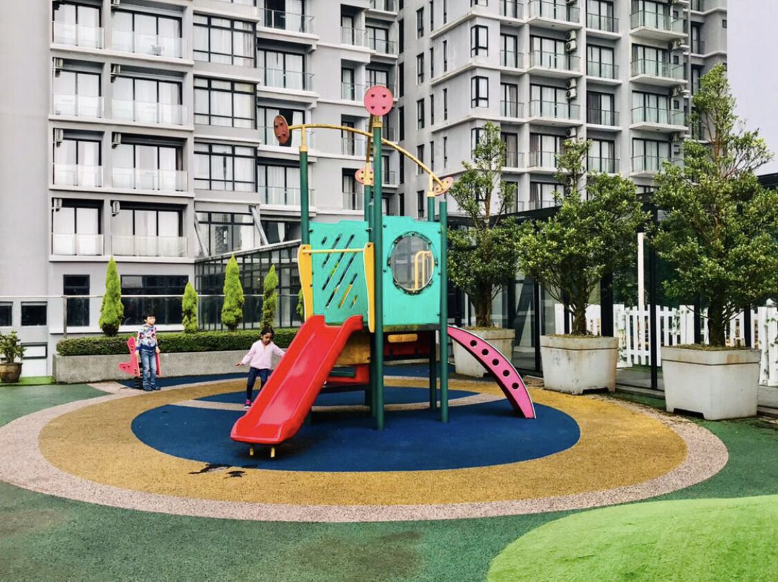 A playground with a slide and climbing structures, surrounded by a circular play area with different colored sections.