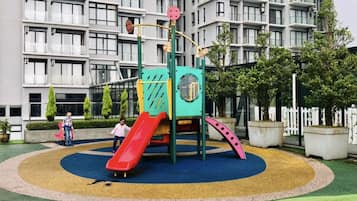 A playground with a slide and climbing structures, surrounded by a circular play area with different colored sections.