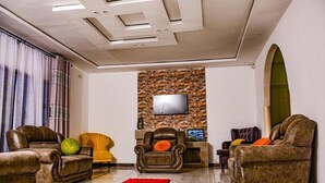 Una sala de estar moderna con sofás de cuero, una alfombra roja y una pared con diseño de ladrillo.