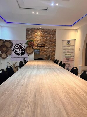 Conference room with a long table and black chairs, featuring a stone accent wall and LED lighting.