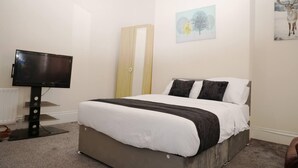 Une chambre d’hôtel avec un lit, un téléviseur à écran plat, une porte et un tableau au mur.