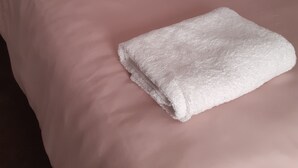 Een bed met een roze dekbed en een witte handdoek.