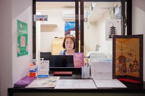 A reception desk with a computer, a sign for Al-Pay, and various informational brochures. - Hostel Gion Sora (Kyoto)