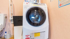 Una lavadora de carga frontal con panel de control, dispensador de detergente y un tendedero fijado a la pared.