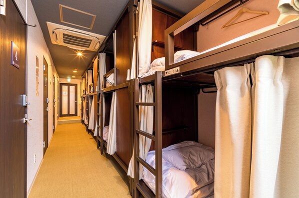 A narrow corridor with bunk beds on both sides, a carpeted floor, and a door at the end. - Hostel Gion Sora (Kyoto)