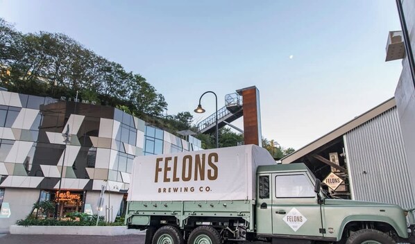 Un camion vert, sur lequel on pouvait lire « Felons Brewing Co. », était garé devant un bâtiment moderne à la façade géométrique.