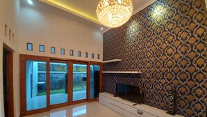 Un salón amplio con una televisión grande, una lámpara moderna y un papel pintado con diseño.